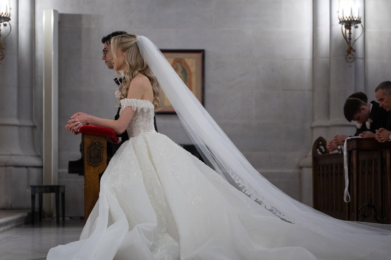 Bride and groom kneeling together in prayer at a cathedral pew