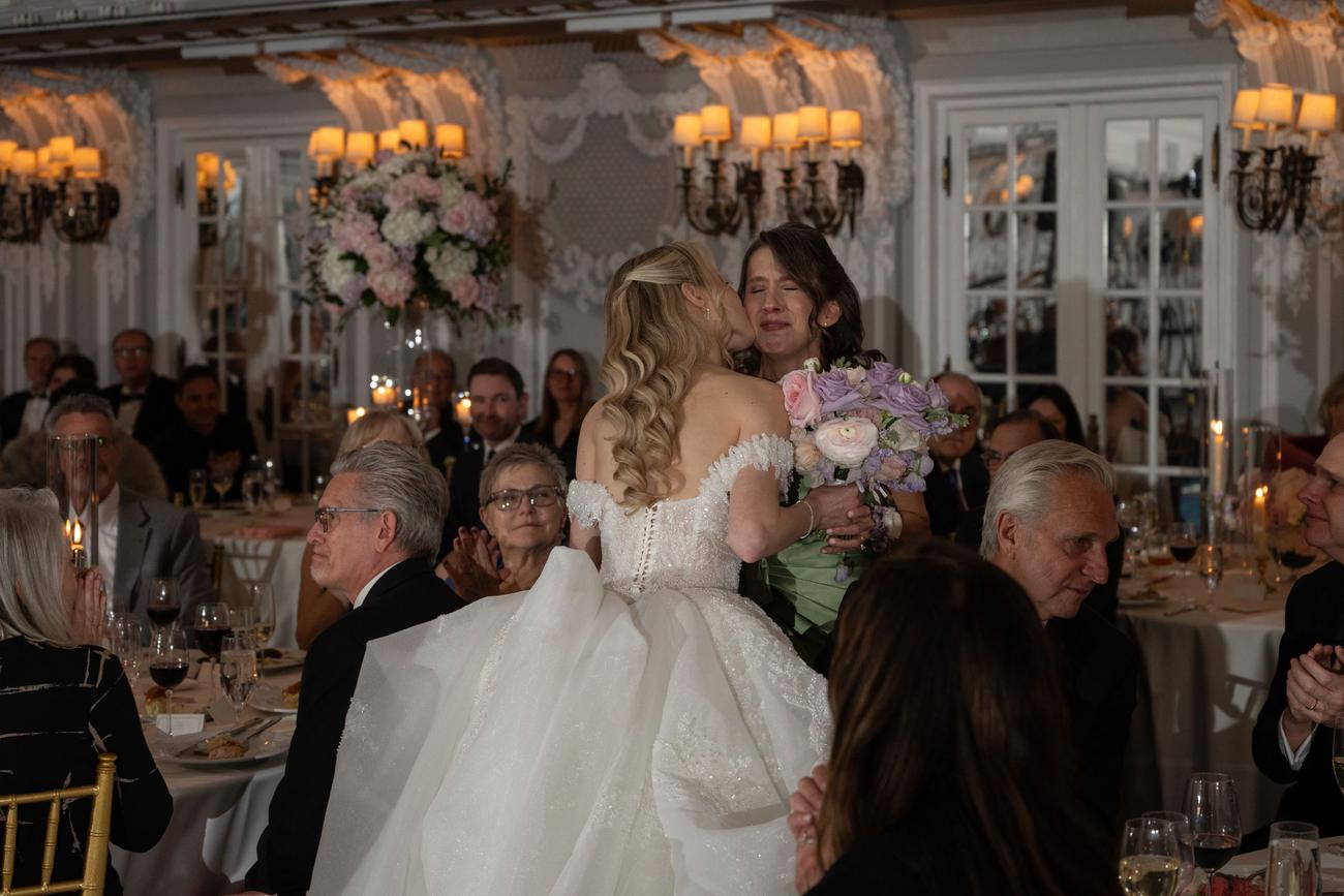 Bride embracing a tearful loved one during a candlelit reception toast