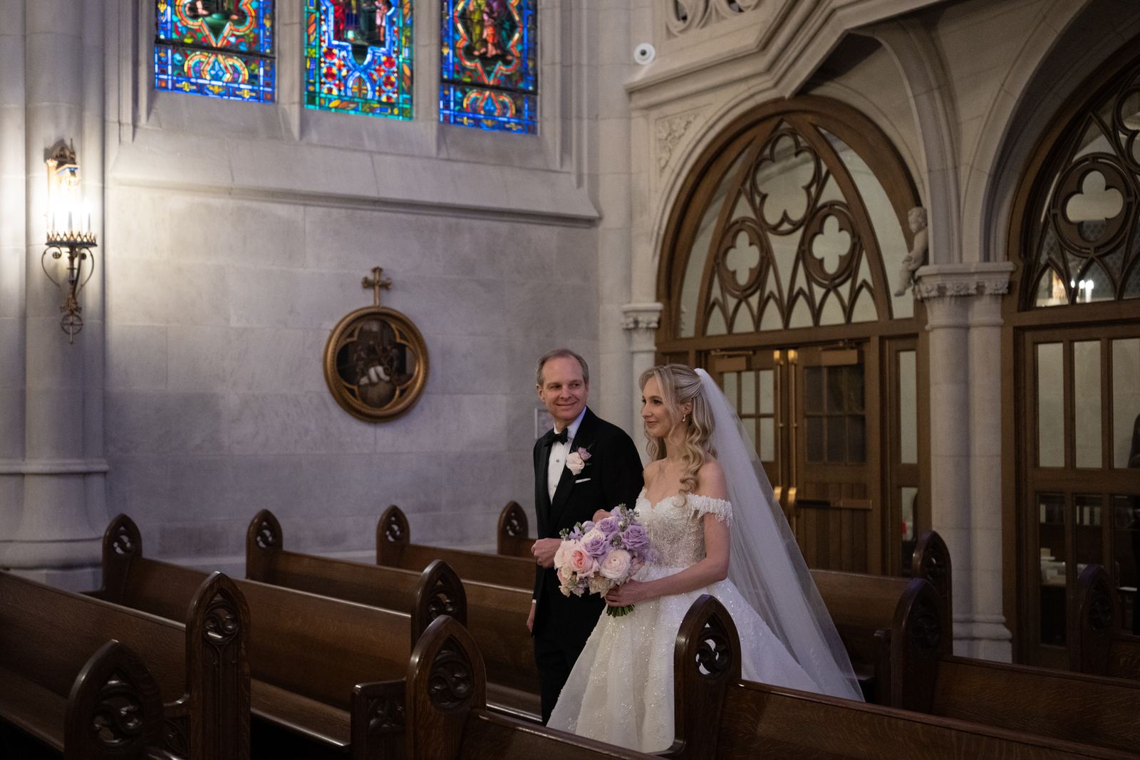 A father walking his daughter down the aisle of a grand cathedral