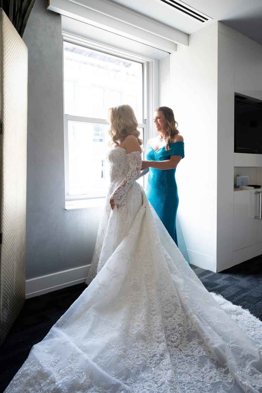 Bride being laced into her gown by window light
