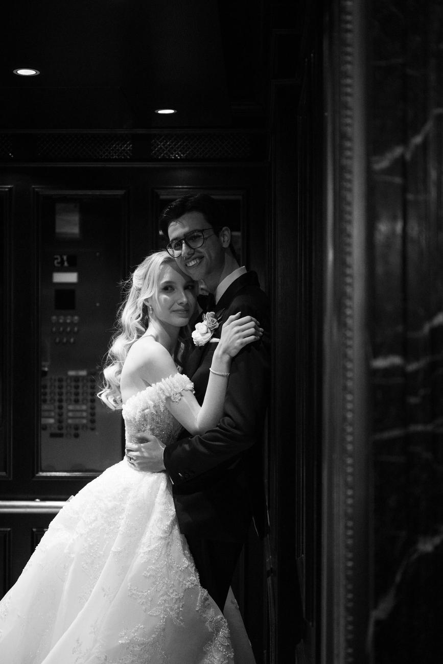 A quiet black and white embrace inside a marble elevator lobby