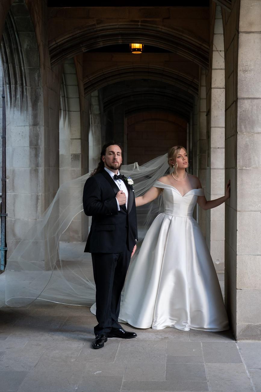 A couple posed formally within a stone colonnade