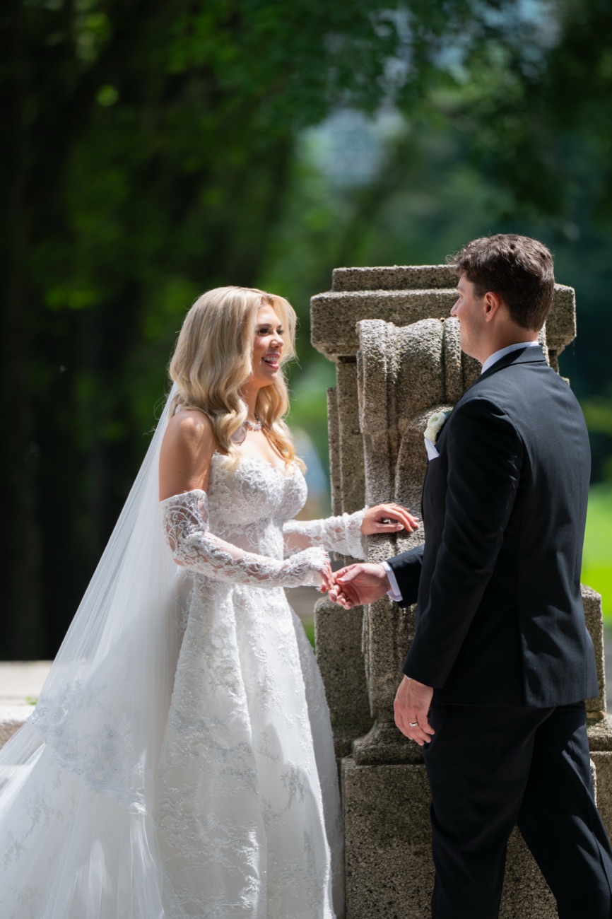 A couple laughing together, hands joined, beside a stone garden balustrade
