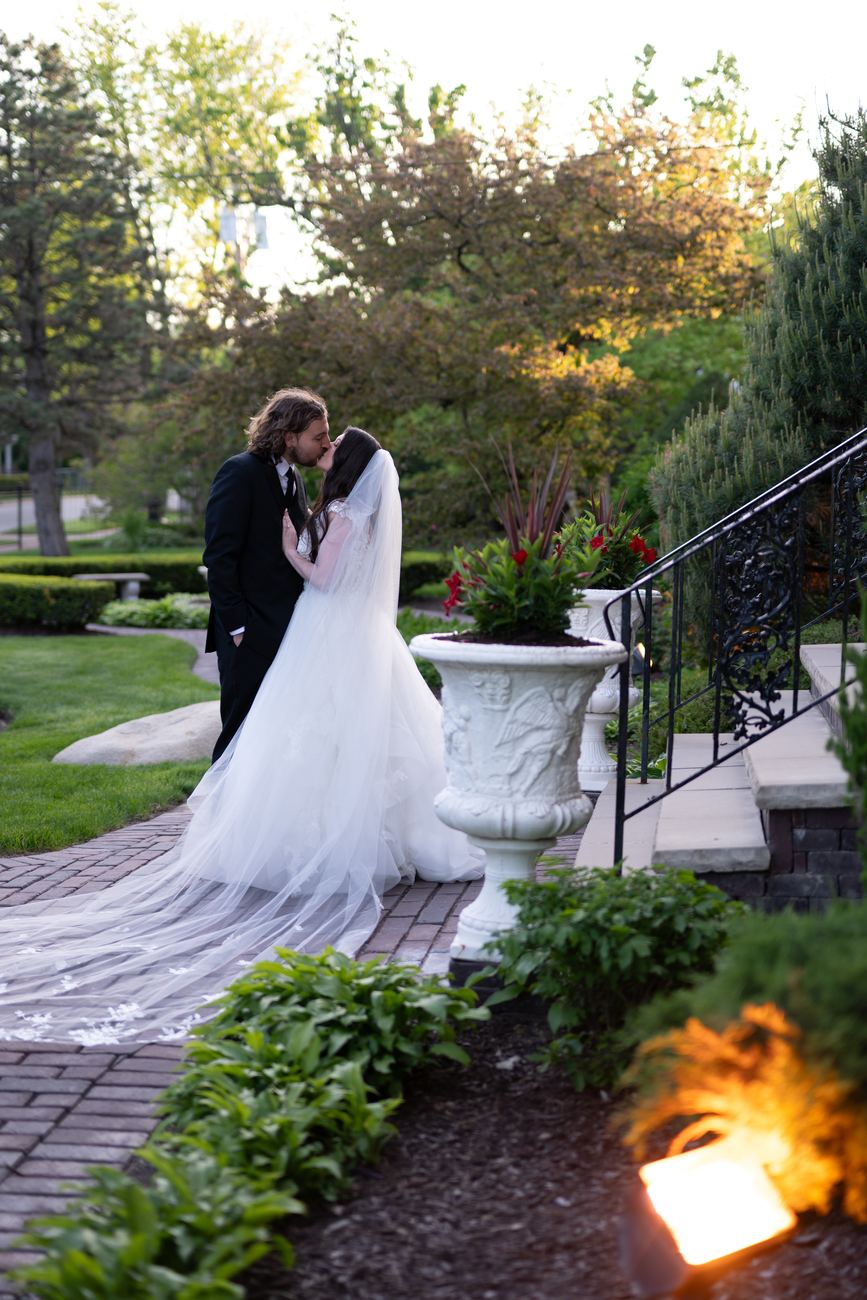 A couple kissing on a garden path at dusk