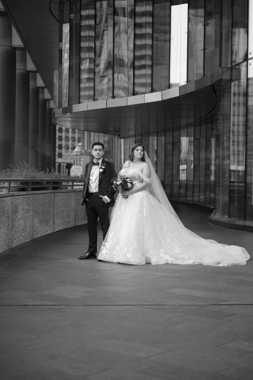 A couple standing together within a modern glass colonnade