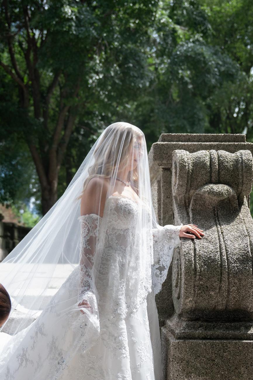 A bride alone in a quiet moment beside a stone balustrade