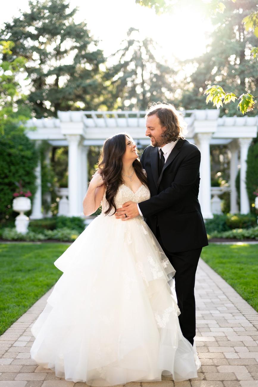 Couple embracing at golden hour beneath a garden pergola