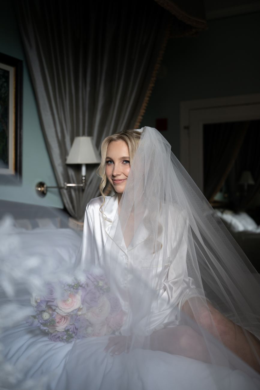 Bride sitting quietly with her bouquet, wrapped in a silk robe