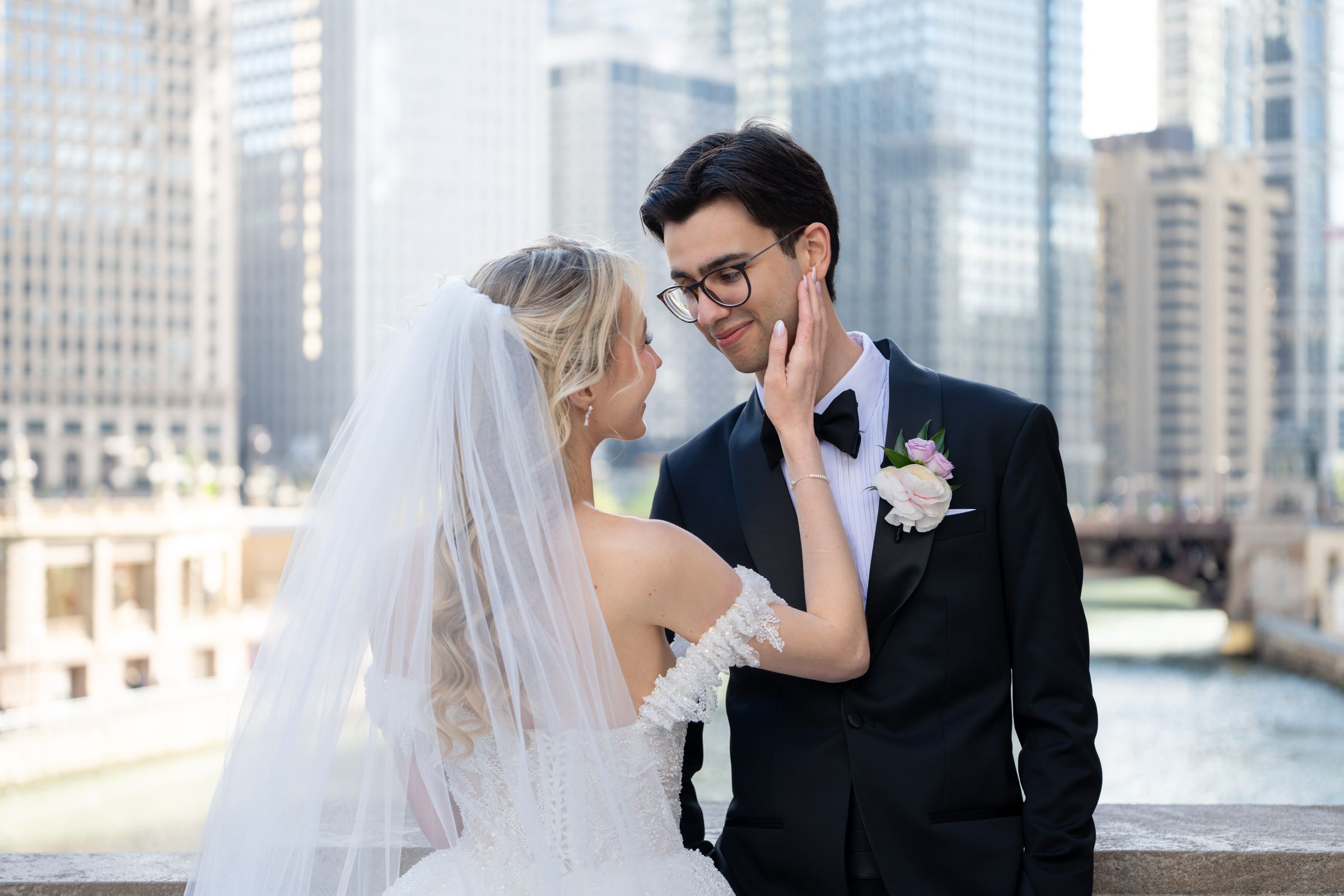 A couple sharing an intimate moment along the Chicago River, skyline behind them