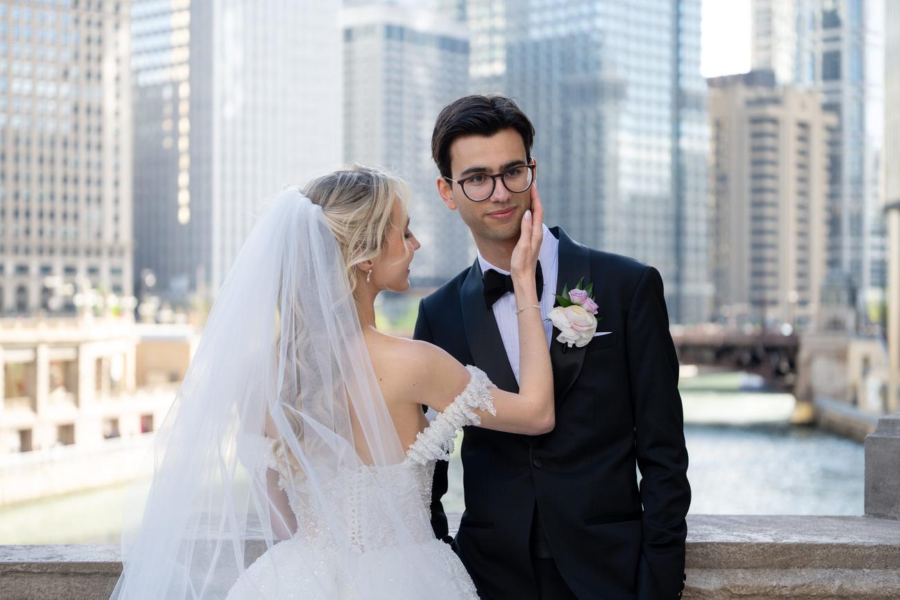 A couple sharing an intimate moment beneath a veil with the city skyline behind them