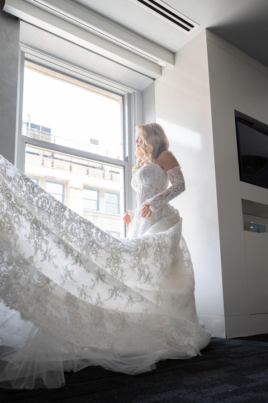 Bride's lace train pooling across the floor of a sunlit hotel suite