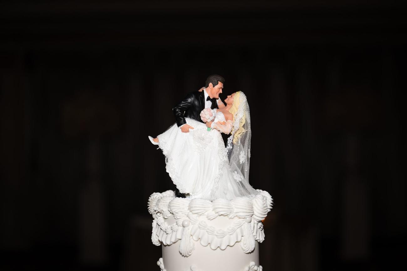 A bride-and-groom cake topper silhouetted atop a candlelit wedding cake