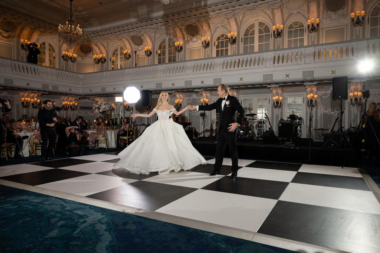 Bride twirling across a black-and-white checkerboard ballroom floor