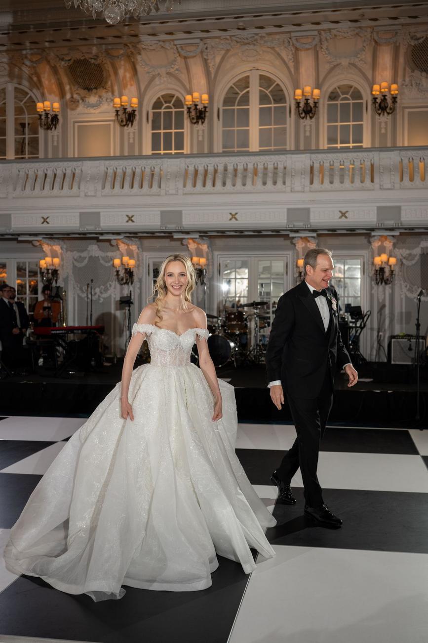 Bride crossing a black-and-white checkerboard ballroom floor