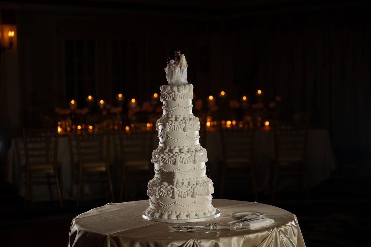 An ornately decorated tiered wedding cake, candlelit
