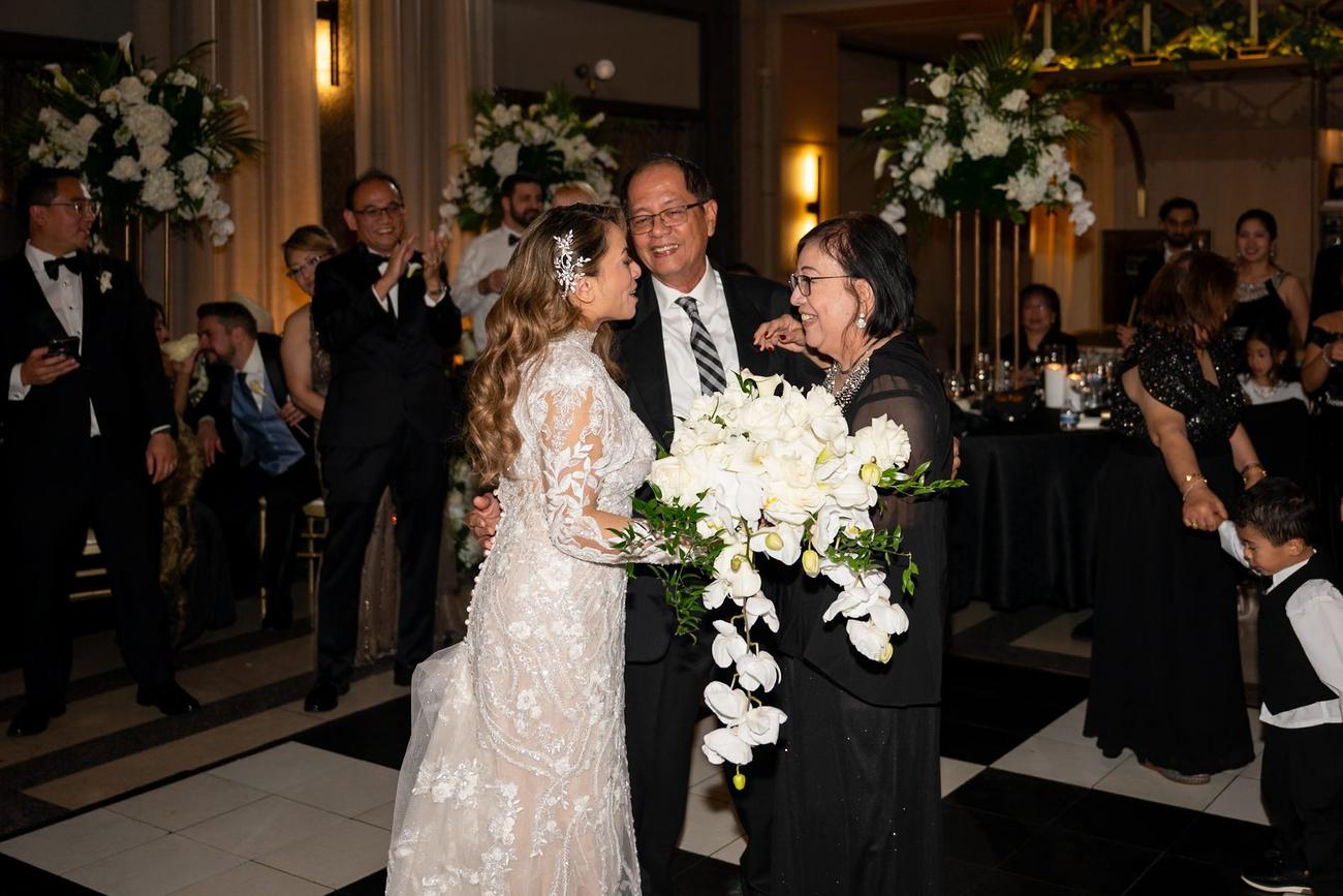 Bride embracing her parents on the dance floor