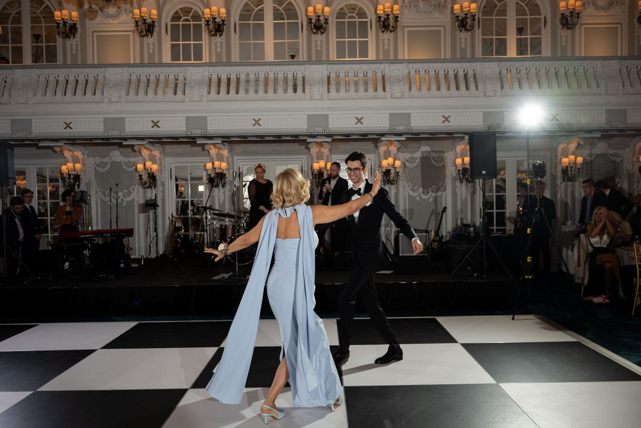 A couple sharing a formal dance on a checkerboard ballroom floor