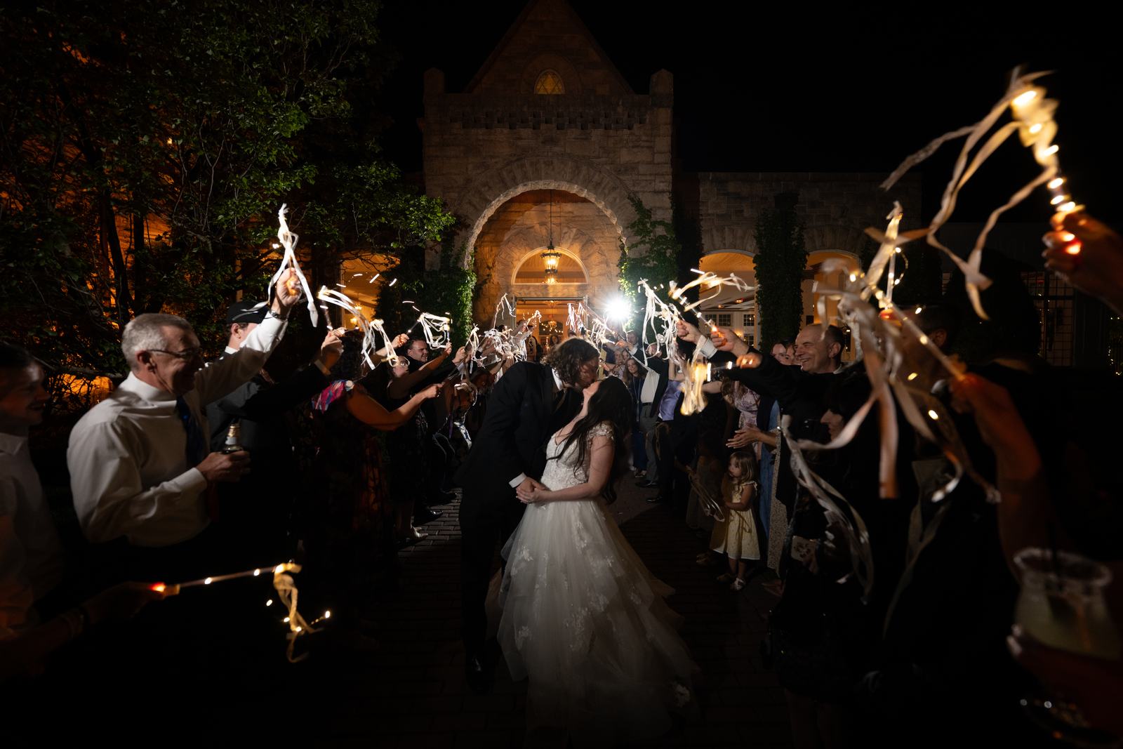 Couple walking through a sparkler send-off tunnel at night