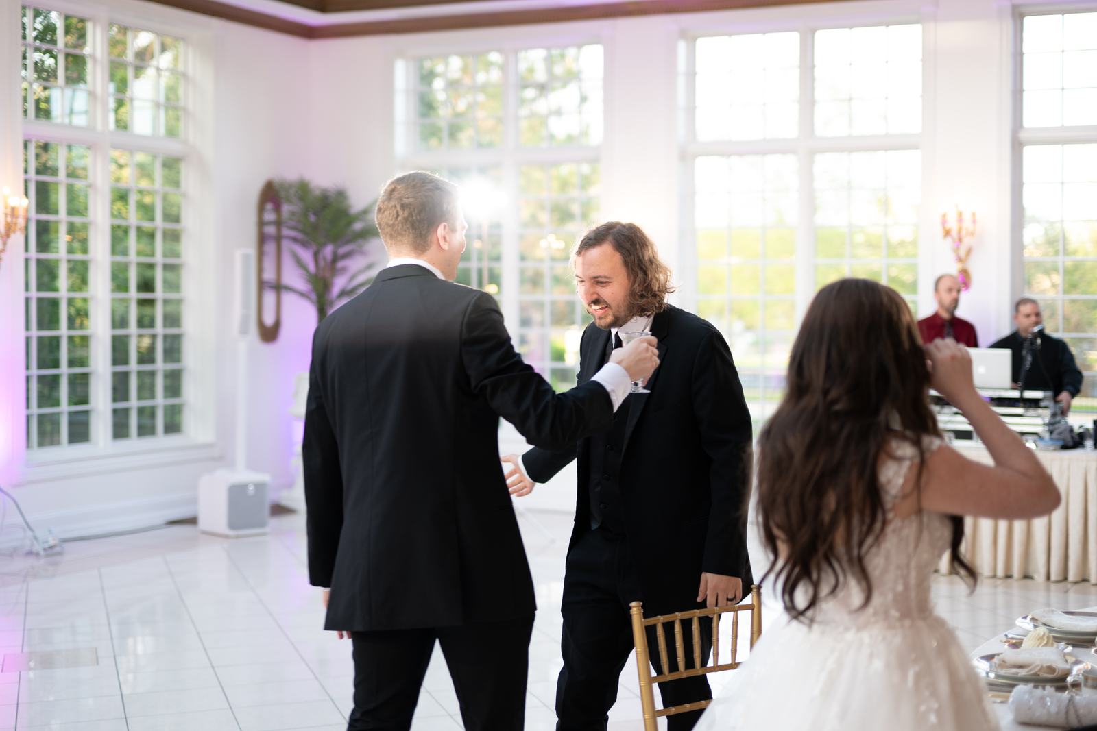 Groomsmen and bride sharing a candid moment beneath a grand staircase