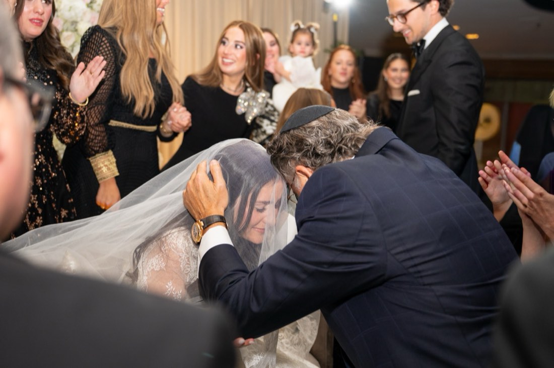 A father kissing his veiled daughter's forehead before the ceremony
