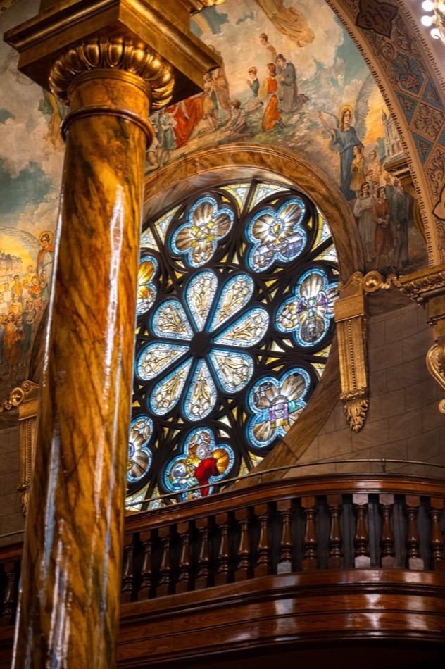 A gilded column beside a stained glass rose window