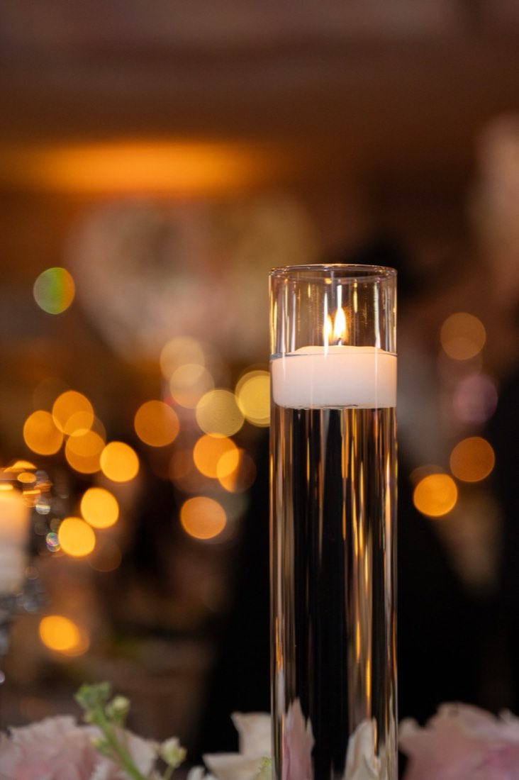 A floating candle glowing against a warm, blurred backdrop of lights