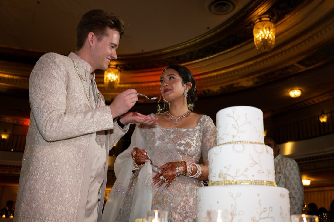 A groom feeding cake to his bride at an Indian-fusion reception