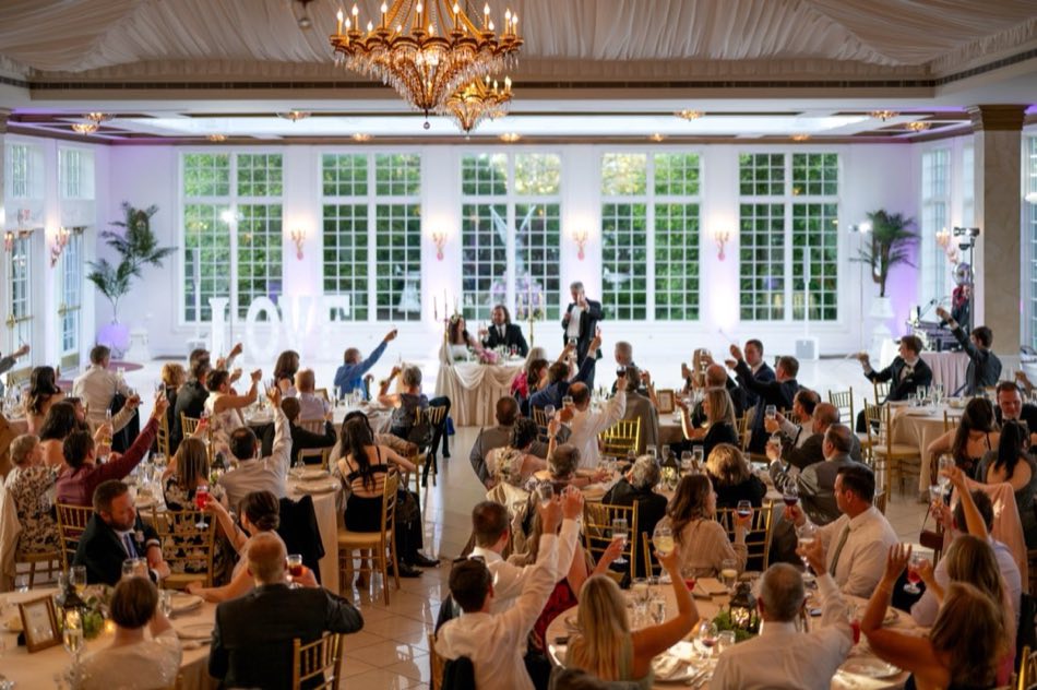 Guests raising their glasses in a toast beside light-up LOVE letters