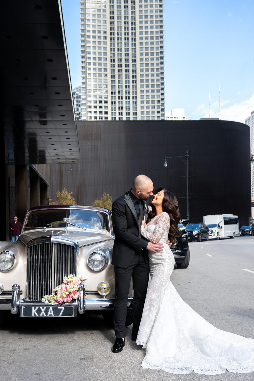 Couple embracing beside a vintage Rolls-Royce at dusk